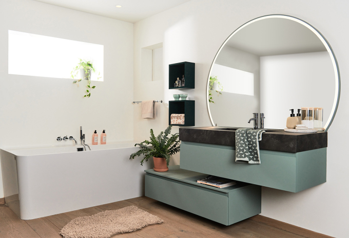 Badkamer met blauw-groen meubel en grote ronde spiegel toonzaal turnhout